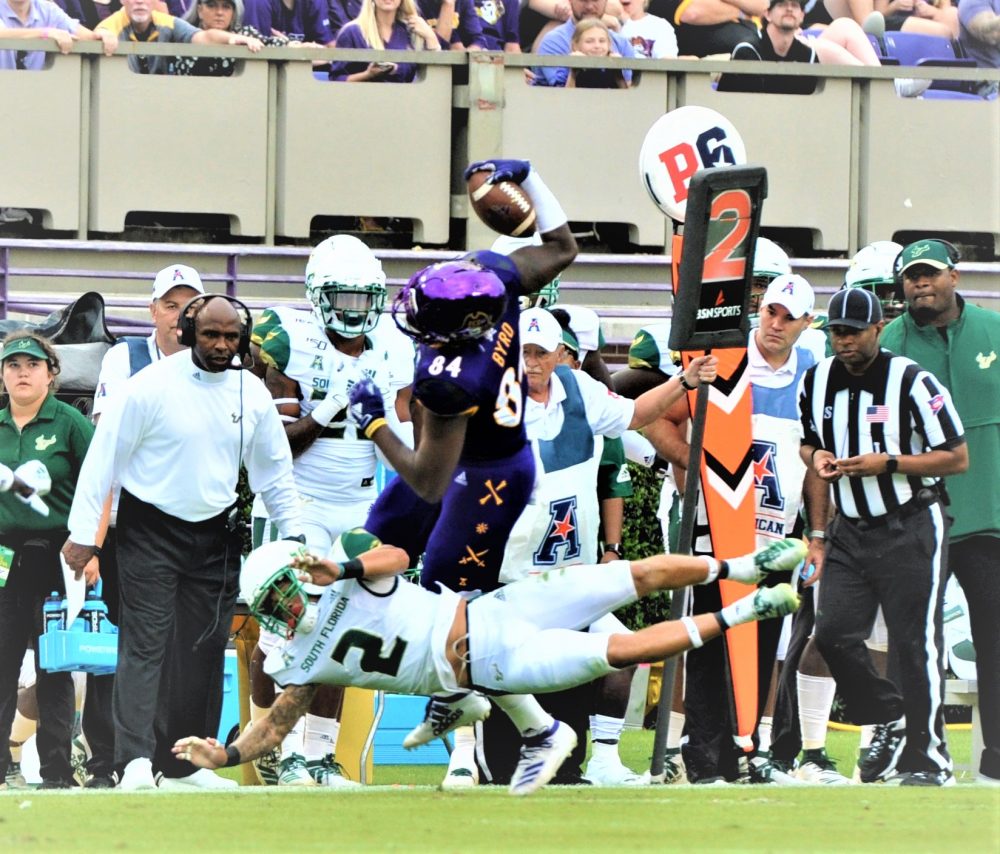 Zech Byrd makes a 5-yard gain on a catch for East Carolina as Nick Roberts (2) makes the stop in front of USF coach Charlie Strong. (Photo by Al Myatt)