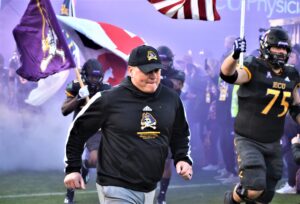 ECU coach Mike Houston and the team flag bearers run onto Bagwell Field during 'Purple Haze.' (Al Myatt photo)